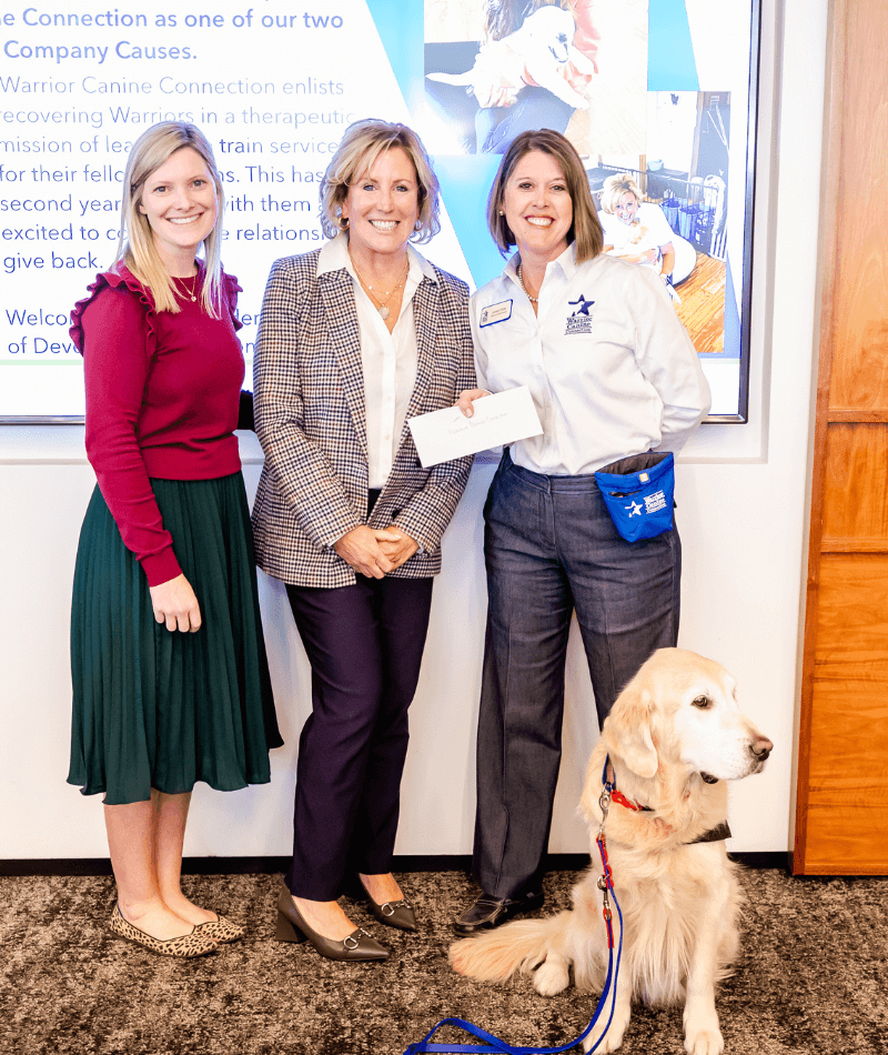 Significance Inc team with Warrior Canine Connection representative and service dog receiving charitable donation