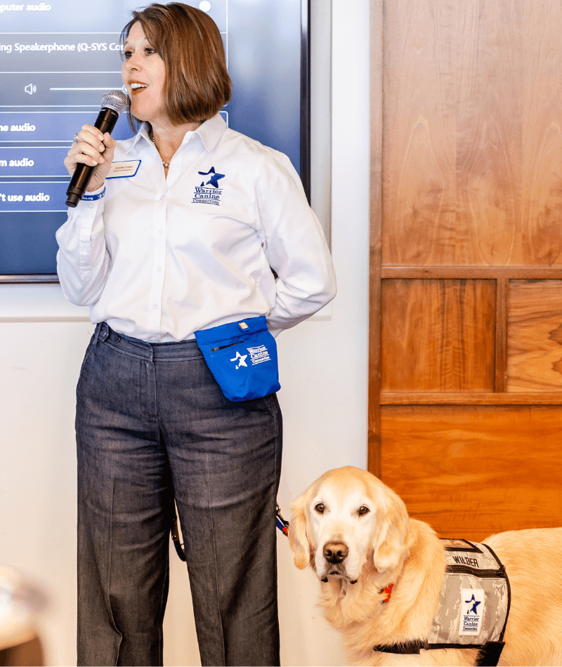 Warrior Canine Connection Representative giving speech at Significance Inc with a Golden Retriever service dog