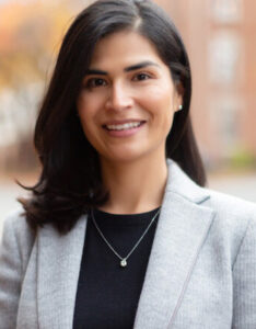 A professional woman in a gray blazer smiling at the camera